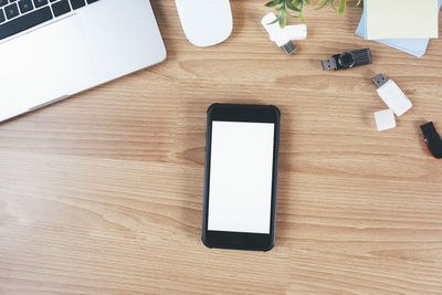 Top view of designer workplace with mock up smartphone on table.