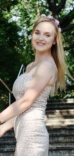 Portrait of young woman standing against trees