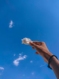 Low angle view of hand against blue sky