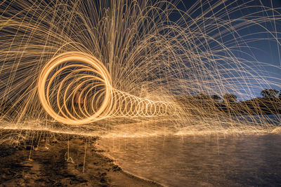 Light trails on beach against sky at night