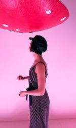 Full length of woman standing against pink background