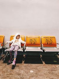 Full length of woman standing on seat against sky