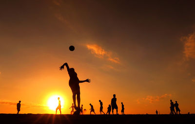 Silhouette of man with arms raised at sunset