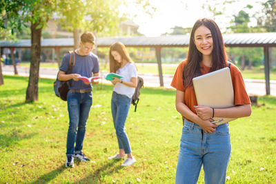 Portrait of woman standing with friends at park