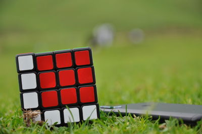 Close-up of puzzle cube with smart phone on grass