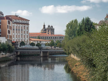 Buildings at waterfront against cloudy sky