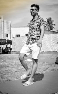 Full length portrait of young man standing against sky
