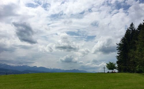 Scenic view of grassy field against cloudy sky
