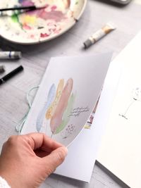 High angle view of person hand holding paper with pen on table