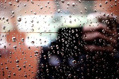 Close-up of wet window against sky