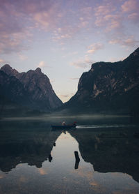 Scenic view of lake by mountains against sky during sunset