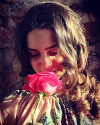 Close-up of young woman smelling pink rose