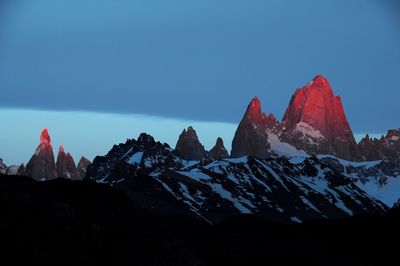 Scenic view of snowcapped mountains against blue sky at dawn