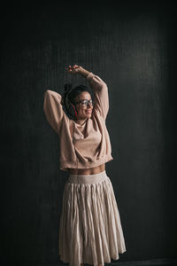 Portrait of young woman standing against black background