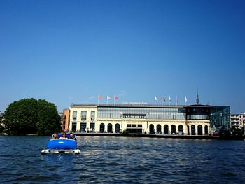 Friends on boats in river against buildings in city