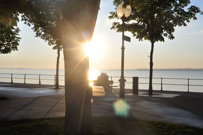 Silhouette railing by river against sky during sunset