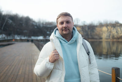 Portrait of young man standing against lake