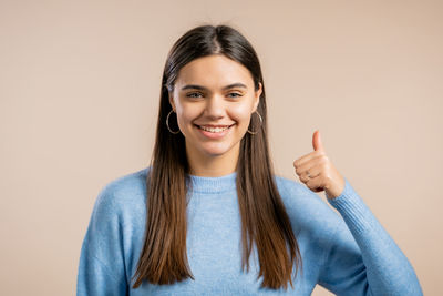 Portrait of a smiling young woman against gray background