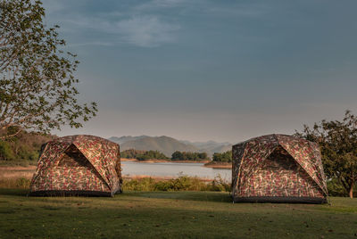 Tent on field by lake against sky