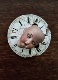 High angle view of doll on weathered clock over table