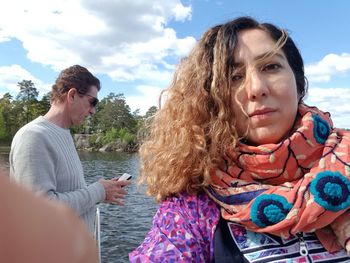 Portrait of woman with man in background against river