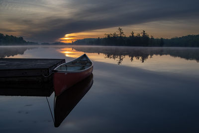 Boat moored in lake during sunset