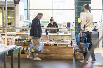 Man buying groceries from saleswoman in organic supermarket