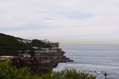 Scenic view of cliff by sea against sky