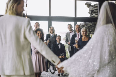Newlywed couple holding hands in front of guests on wedding day