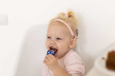 Portrait of cute girl eating lollipop against white background