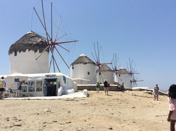 People on beach against clear blue sky