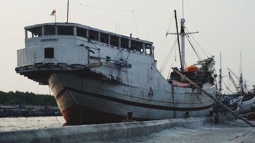 Fishing boat moored at harbor against sky