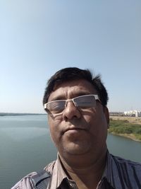 Portrait of young man wearing sunglasses against clear sky