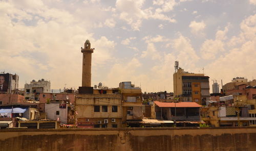 Buildings in city against cloudy sky