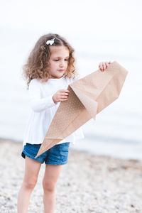 Girl holding origami paper at beach