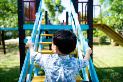 Rear view of boy on slide at playground