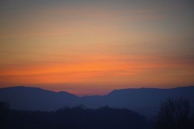 Scenic view of silhouette mountains against romantic sky at sunset