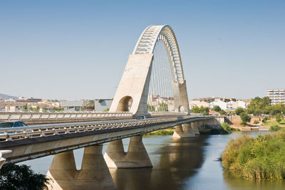 Bridge over river in city against clear sky