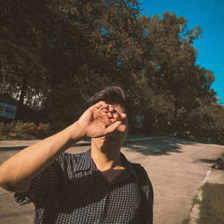 Portrait of woman standing by tree in city