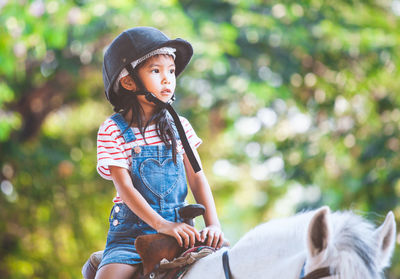 Girl riding horse against trees