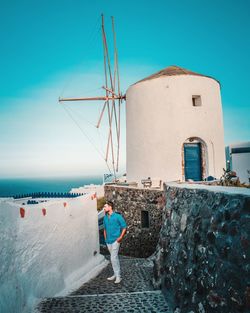 Woman standing by sea against clear blue sky