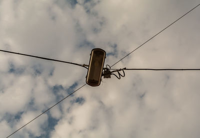 Low angle view of bird perching on cable against sky