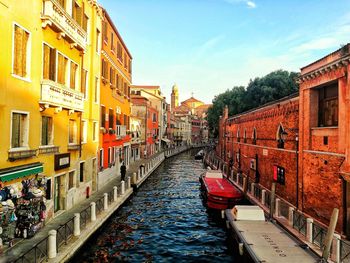 Canal amidst buildings in city against sky