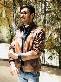 Young man wearing mask standing against trees