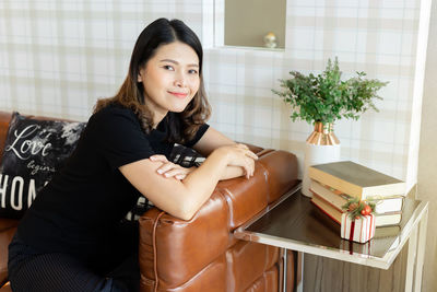 Portrait of young woman sitting on seat at home