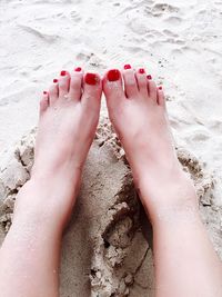Low section of woman feet on sand
