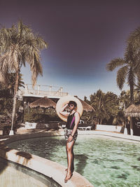 Portrait of young woman in swimming pool against sky