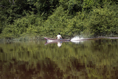 Full length of person on lake against trees in forest