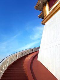 Low angle view of bridge over building against blue sky