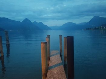 Pier over lake against mountains and cloudy sky